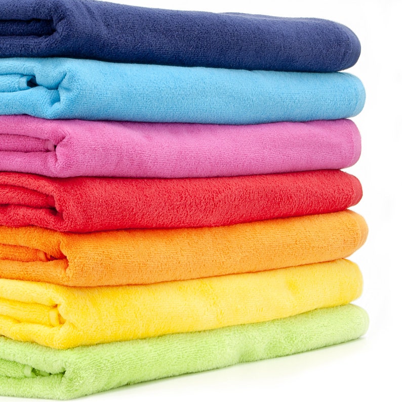 May include: A stack of seven colorful towels in various shades of blue, light blue, pink, red, orange, yellow, and green. The towels are folded and stacked on top of each other.