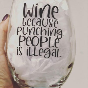 May include: A clear glass wine glass with a black vinyl decal that reads "wine because punching people is illegal".