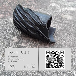 Puede incluir: Un brazalete de cuero negro que presenta una serie de crestas diagonales elevadas en su superficie. Debajo del brazalete hay un gr&aacute;fico rectangular que contiene el texto JOIN US! Subscribe to the newsletter and save 15% on your first order, junto a un c&oacute;digo QR.