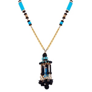 May include: A gold chain necklace with a blue and black pendant. The pendant is made of beads and has a cylindrical shape.