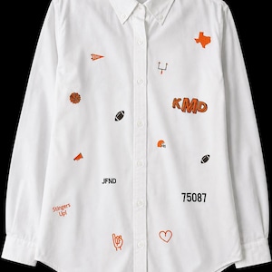 May include: A white long-sleeve button-down shirt featuring various orange and black embroidered icons and text, including a Texas map, footballs, a helmet, a megaphone, a pom-pom, the letters KMD, JFND, the number 75087, and the text Stingers Up!