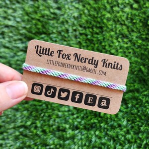 May include: A brown card with the text "Little Fox Nerdy Knits" and the email address "littlefoxnerdyknits@gmail.com". The card also has social media icons for Instagram, TikTok, Twitter, Facebook, Etsy, and Amazon.