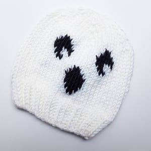 May include: White knitted hat with black polka dots. The hat is shaped like a ghost.