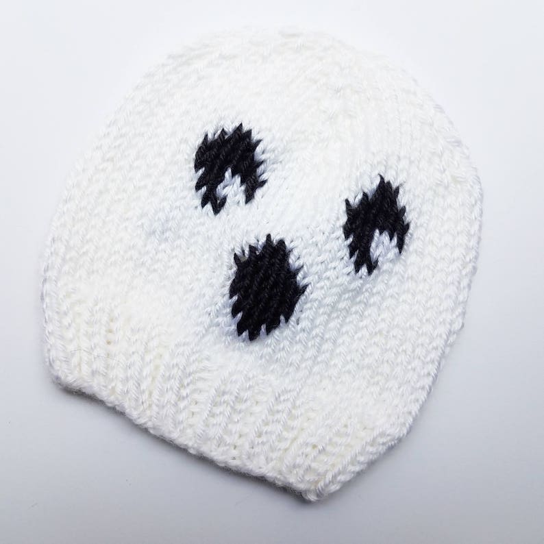May include: White knitted hat with black polka dots. The hat is shaped like a ghost.