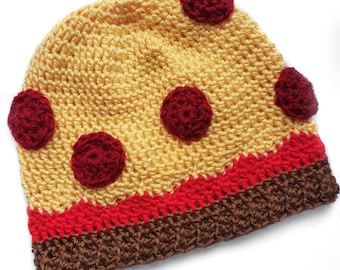 May include: A crocheted hat shaped like a pizza with red pepperoni and a brown crust.