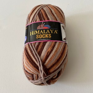 May include: A ball of brown, beige, and white striped yarn with a label that reads "HIMALAYA SOCKS" and "www.himalaya.com.tr"