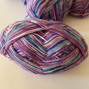 May include: A ball of yarn with a multi-colored striped pattern in shades of pink, purple, blue, and white.