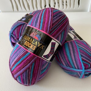 May include: Two balls of Himalaya Socks yarn in a multi-colored striped pattern of purple, blue, and pink. The yarn is labeled "Himalaya Socks" with the website address "www.himalaya.com.tr".