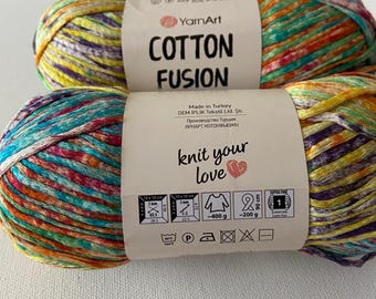 May include: Two skeins of YarnArt Cotton Fusion yarn in a multi-colored pattern. The yarn is super fine and comes in a 400 gram skein. The label includes care instructions and information about the yarn.