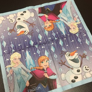 Puede incluir: Una servilleta de papel azul y morada con un dise&ntilde;o que presenta personajes de la pel&iacute;cula de Disney Frozen. Los personajes incluyen a Elsa, Anna y Olaf. El texto "From the movie" y "Disney's FROZEN" est&aacute; impreso en la servilleta.