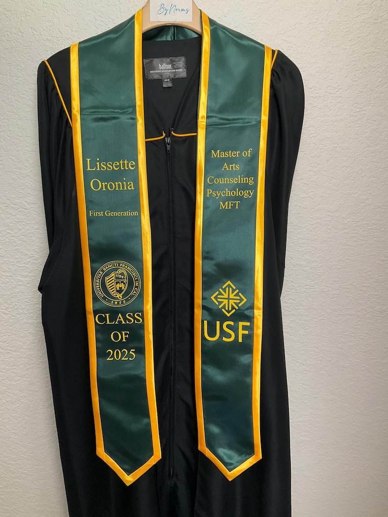 May include: Green and gold graduation stole with the text "Lissette Oronia, First Generation, Class of 2025, USF, Master of Arts Counseling Psychology MFT"