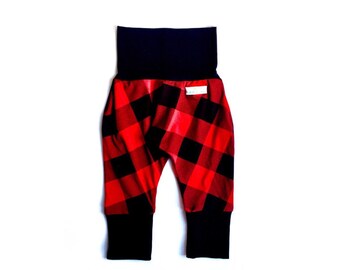 Op de afbeelding: Rode en zwarte geruite broek met een zwarte tailleband en zwarte boorden. De broek heeft een losse pasvorm en is gemaakt van een zachte, comfortabele stof.