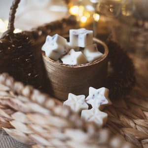 May include: A wooden bowl filled with white star-shaped wax melts, sitting on a woven basket. The wax melts have a subtle lavender scent.