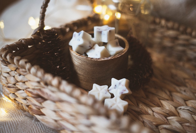 May include: A wooden bowl filled with white star-shaped wax melts, sitting on a woven basket. The wax melts have a subtle lavender scent.