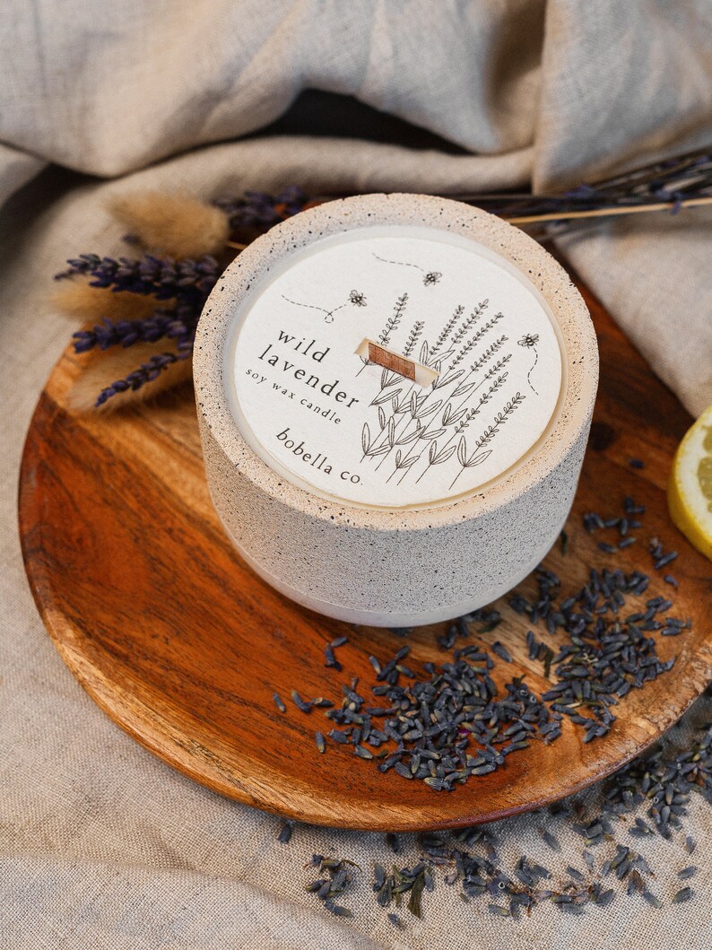 May include: A white concrete candle jar with a black and white illustration of lavender flowers and bees. The label reads "wild lavender soy wax candle bobella co."