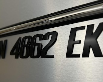 May include: Black license plate with white letters and numbers. The plate reads "TN 4862 EK".