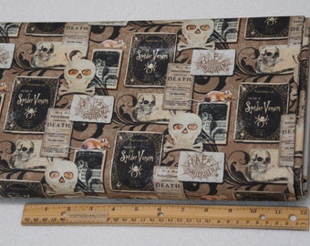 May include: Halloween-themed fabric featuring a repeating pattern of skulls, spiderwebs, and vintage book covers with the text "Spider Venom" and "Death". The fabric is primarily brown with black and cream-colored accents. A ruler is placed at the bottom.