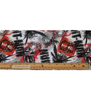 May include: A white fabric featuring a repeating graphic print of black wasps and red-accented figures, with a wooden ruler placed along the bottom edge showing a length of 12 inches. The pattern includes bold black brushstroke textures.