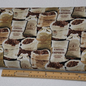 May include: Fabric with a repeating pattern of coffee bean sacks. The sacks are beige and brown, filled with coffee beans, and labeled "Coffee Imports" and "Premium". The background is black.