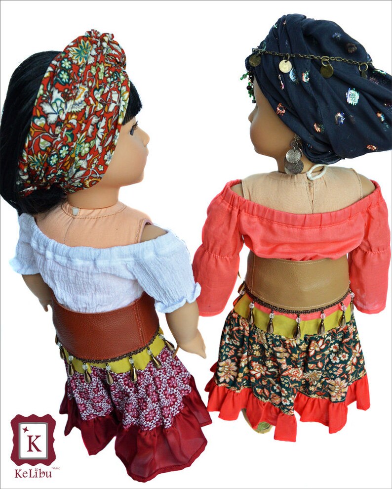 Back view of the fortune teller costumes.  One doll wears a white, off-the-shoulder shirt, a red floral headscarf, red belt and a red/floral/yellow skirt.  The other doll wears a black headscarf, salmon shirt, brown belt and green floral skirt.