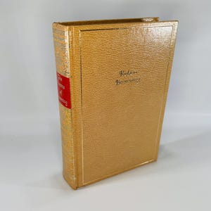 May include: A hardcover book with a textured, tan cover. The spine has a red label with white text that reads "The Poems of Browning." The title "Robert Browning" is printed in gold on the front cover.