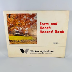 May include: A vintage "Farm and Ranch Record Book" with a scenic autumn landscape on the cover. The title is in red, and the book is from Wickes Agriculture, a division of the Wickes Corporation.