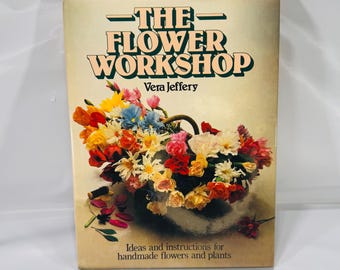 May include: A vintage book titled "The Flower Workshop" by Vera Jeffery. The cover features a colorful bouquet of handmade flowers in a basket. The book provides ideas and instructions for creating handmade flowers and plants.