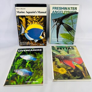 May include: Four books on aquatic life. Titles include "Marine Aquarist's Manual", "Freshwater Angelfishes", "Livebearers", and "Bettas". The covers feature images of fish and aquatic plants. The books are in good condition and appear to be vintage.