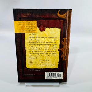 May include: A hardcover book with a brown cover and a yellow banner. The book features text from "Red Dragon Codex" and a letter. The back cover includes text from the author and a barcode.