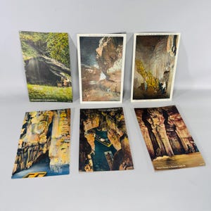 May include: Six vintage postcards featuring images of caves and natural formations. The postcards depict various scenes, including waterfalls, cave interiors with stalactites, and boat tours. The color palette includes greens, browns, and blues.