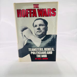 May include: A hardcover book titled "The Hoffa Wars" with red lettering. The cover features a black and white portrait of a man and the text "Teamsters, Rebels, Politicians and the Mob" by Dan E. Moldea.