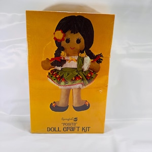 May include: A Springbok "Posita" doll craft kit featuring a colorful doll with black hair, a green skirt, and red and white accents. The box is yellow with the doll's image and the text "Springbok "Posita" Doll Craft Kit".