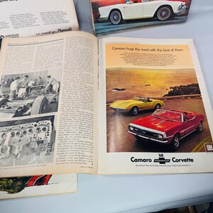 May include: Open magazine pages with vintage car adverts. One advert features a red and yellow convertible Camaro and Corvette. The text reads "Camaro hugs the road with the best of them." Other pages show car parts and text.