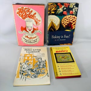 May include: Four vintage cookbooks are displayed. The titles include "Let's Celebrate", "Baking is Fun!", "Prevention's Better Living Cookbook", and "Heloise's Housekeeping Hints". The books feature colorful covers with illustrations and text.