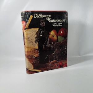 May include: A book titled "Dictionary of Gastronomy" by Andre L. Simon & Robin Howe. The cover features a still life of food and drink, including cheese, bread, wine, grapes, and fruit.