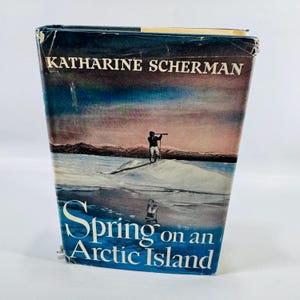 May include: A vintage book titled "Spring on an Arctic Island" by Katharine Scherman. The cover features a landscape with a person observing the horizon. The title is in white and blue, set against a backdrop of a snowy island and a dusky sky.