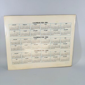 Pu&ograve; includere: Un calendario vintage per gli anni 1981, 1982 e 1983. Il calendario &egrave; stampato su carta color crema e presenta un layout semplice con i mesi e i giorni della settimana. Il testo "CALENDAR FOR" &egrave; stampato in alto.