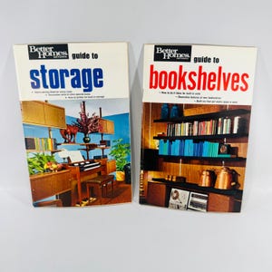 May include: Two Better Homes and Gardens guide books titled guide to storage and guide to bookshelves. The storage book cover features a wooden shelving unit with a piano, while the bookshelves book cover displays wooden shelves filled with books.