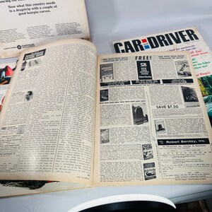May include: An open vintage magazine, titled "Car and Driver," with yellowed pages. The text is in black, and there are various articles and advertisements. The magazine is open to a spread with text and images.