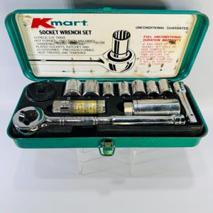 May include: A vintage Kmart 13-piece 3/8" drive socket wrench set in a green metal case. The set includes various chrome-plated sockets, a ratchet, and accessories. The case has text that reads "Unconditional Guarantee".