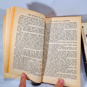 May include: Open book with text from a fantasy novel, featuring the title "The Swords of Lankhmar." The pages are yellowed, suggesting age. The text is in English, with a focus on adventure and intrigue.