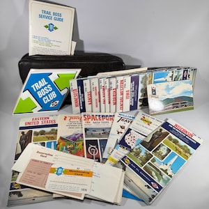 May include: A collection of vintage travel ephemera, including a Trail Boss Service Guide, club sign, and various state maps from the 1970s. The items are in a black case and include a membership card and brochures from Sun Oil Company.