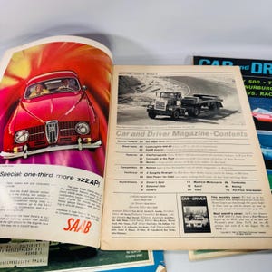 May include: A spread of vintage car magazines, one with a red Saab car advert and the text "SAAB Special: one-third more zzzAP!". The other page shows a black and white image of a truck and the magazine's contents. The magazines are open.