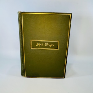 May include: A hardcover book with a dark green cover and gold trim. The title "Alfred Tennyson" is printed in gold lettering on a rectangular gold frame. The book's spine is also dark green with gold accents.