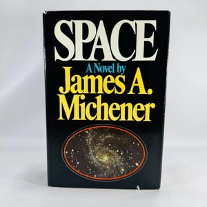 May include: A hardcover book titled "SPACE" by James A. Michener. The cover is black with white and yellow lettering. An oval image of a galaxy is featured on the front cover.