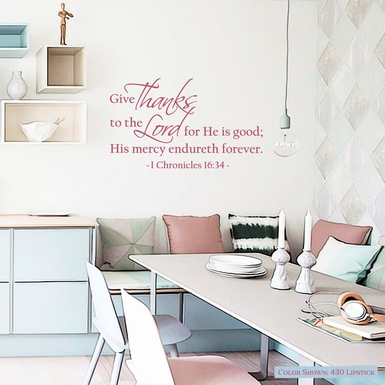 May include: A pink and white dining room with a table and chairs. The wall has a pink vinyl decal with the text "Give thanks to the Lord for He is good; His mercy endureth forever. - I Chronicles 16:34 -"