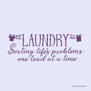 May include: A violet-colored laundry room wall decal with the word "LAUNDRY" in a decorative font. The text "Sorting life's problems one load at a time" is below. Small clothing silhouettes are above the word "LAUNDRY".