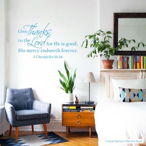 May include: A wall decal with a blue and white design that reads "Give thanks to the Lord for He is good; His mercy endureth forever. - I Chronicles 16:34 -" The decal is shown in a living room setting with a chair, a side table, a bed, and plants.