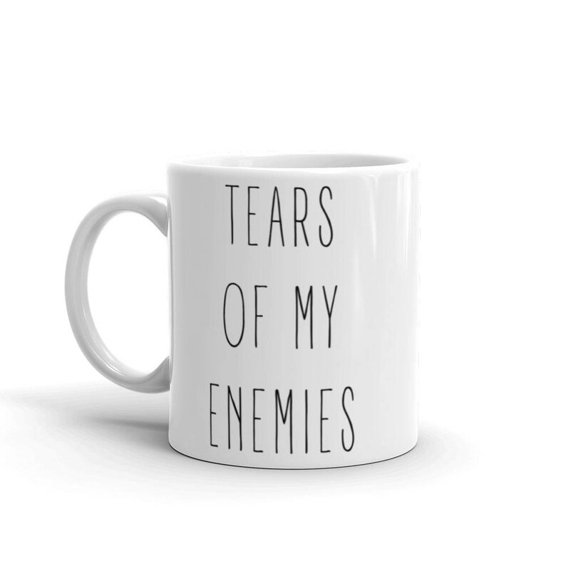 May include: White ceramic coffee mug with black text that reads "Tears of my enemies".