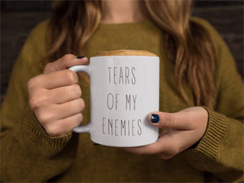 May include: White ceramic coffee mug with black text that reads "Tears of my enemies".